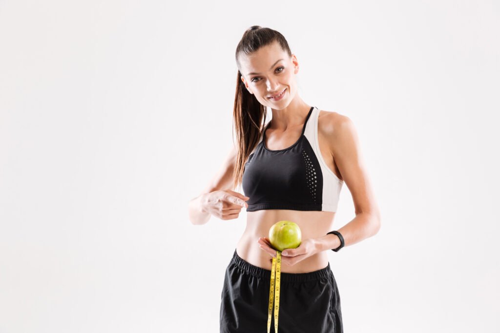 Portrait of a smiling young fitness woman holding green apple